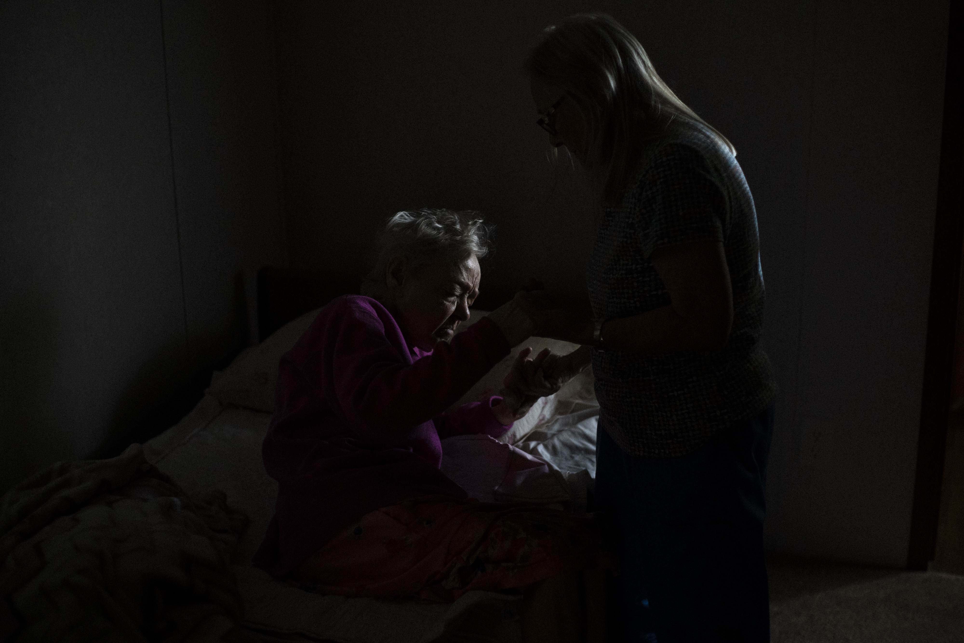 A photograph of Daleann 'Sissy' Garza-Ray helping her mother, Joann, out of bed in Mission, Texas, in July 2021.