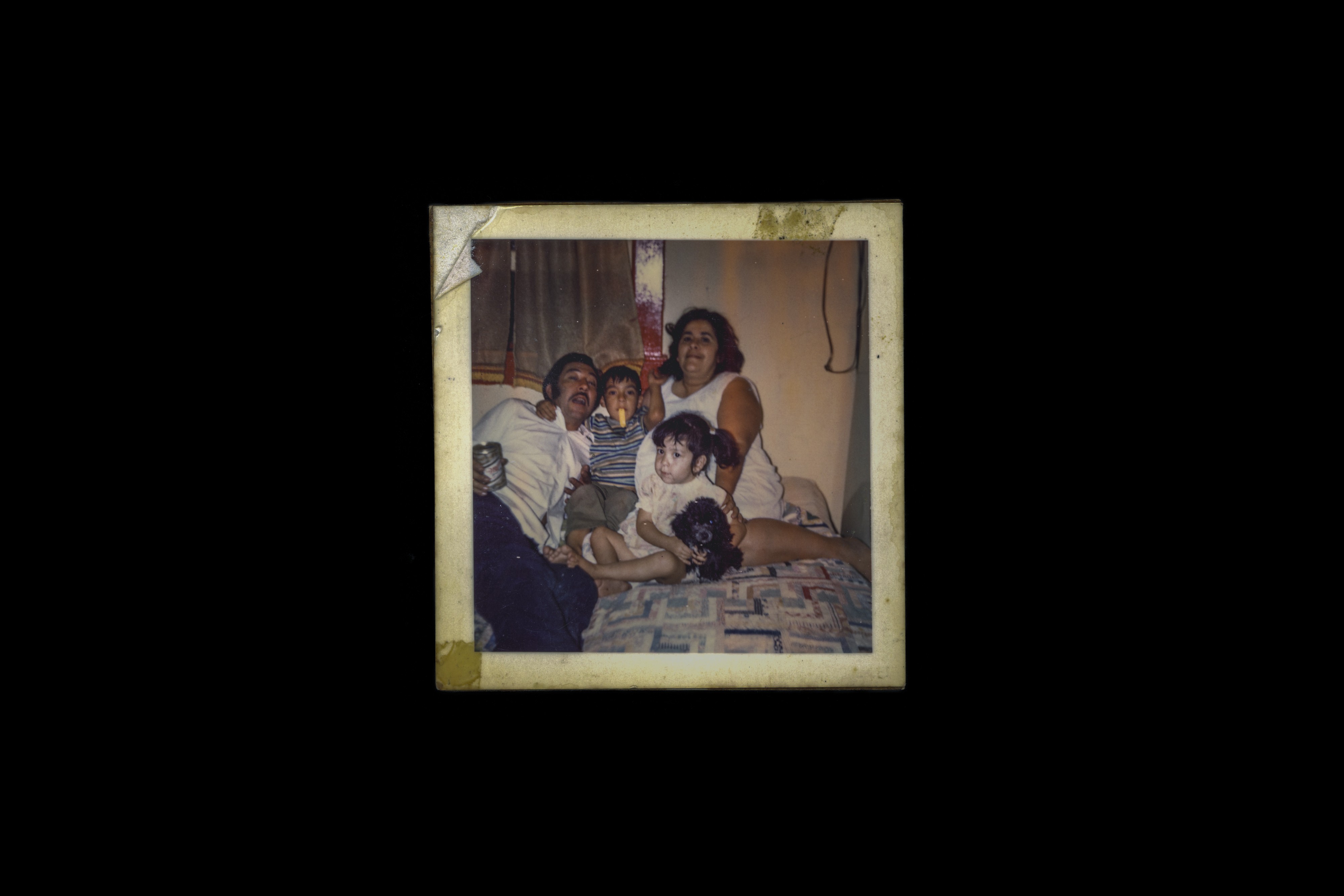 A photograph of the Saenz family—Pancho, Amaro, Manny, and Carmen—together in bed at home in the 1970s.